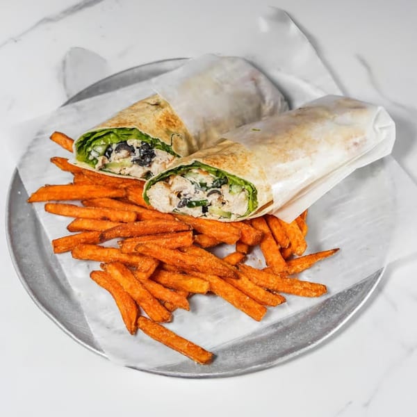 Two chicken wraps with black olives and lettuce, served with a side of sweet potato fries.