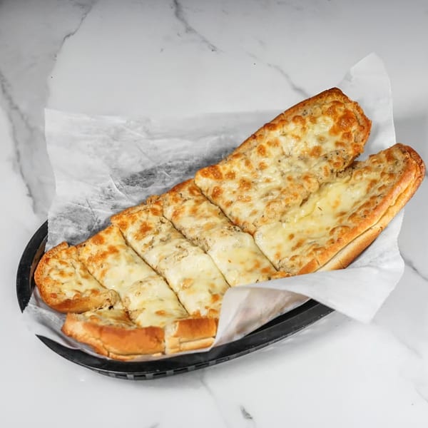 Cheesy garlic bread, sliced and served in a black basket lined with white paper, on a marble surface.