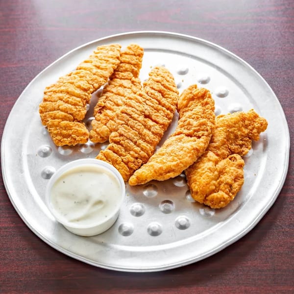 Golden-brown chicken tenders and a small cup of dipping sauce on a round metal tray.