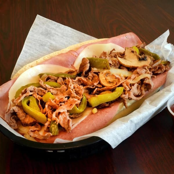 A 5 Herb Pizza Italian cheesesteak with peppers, onions, and mushrooms in a basket.